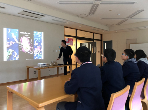 青井准教授から研究について説明を受けています。 青井准教授から研究について説明を受けています。