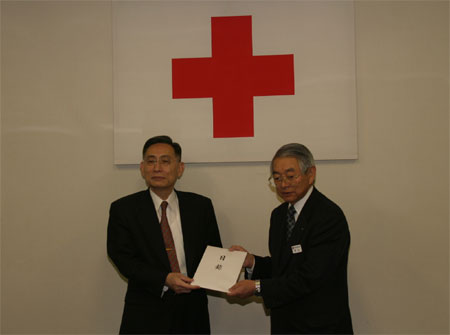 曽山事務局長（右）に義援金を寄託する牟田学長（左）