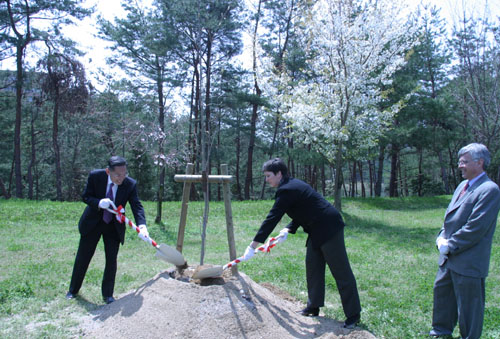 砂糖かえでの木を記念植樹するエスター人文学部長（右）と牟田学長
