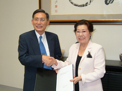 契約書に調印をすませ握手する佐竹代表（右）と牟田学長（左）