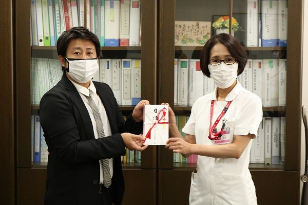 クーポンの目録を吉井副社長(左)から受け取った佐藤部長 クーポンの目録を吉井副社長(左)から受け取った佐藤部長