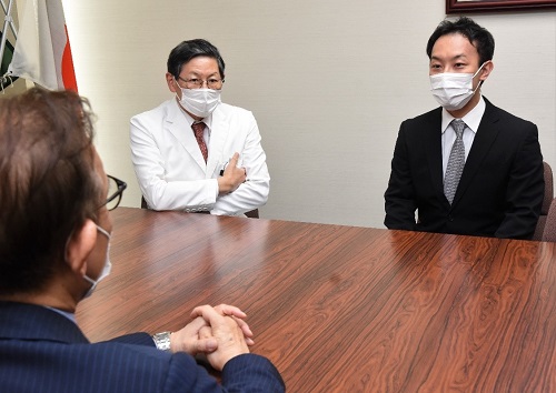 安達病院長(手前)に報告する中医師(右) 安達病院長(手前)に報告する中医師(右)