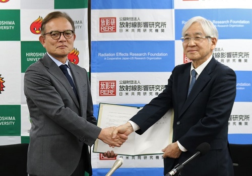 協定書に署名し、握手する安達病院長(左)と神谷理事長 協定書に署名し、握手する安達病院長(左)と神谷理事長