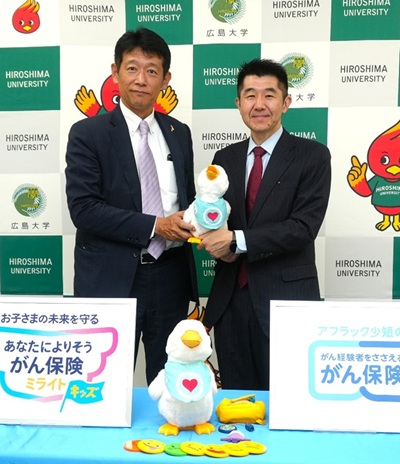 大塚総合支社長(左)からアヒル型ロボットを受け取る岡田教授