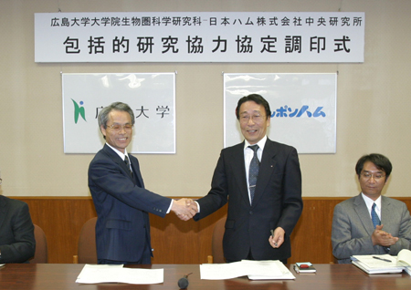 済ませ握手する鈴木研究科長（左）と山田研究所長（右）　
