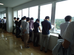 食堂の展望窓から工場内を見学する学生たち