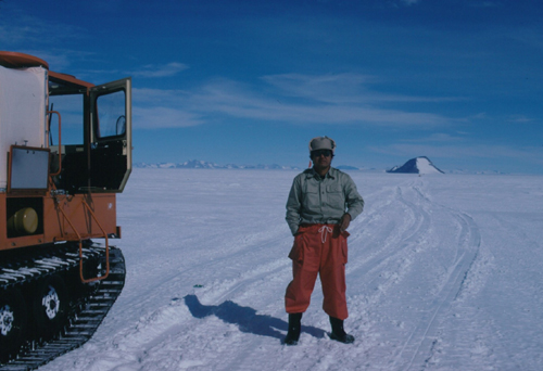 第２９次隊の雪上輸送オペレーション中の神田啓史氏。遠方にセールロンダーネ山脈の輸送オペレーション，近くにロムナエス岩を望む。１９８７年１２月