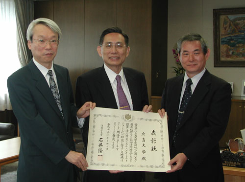 表彰状を手に，左から塩谷事務局長，牟田学長，神谷施設部長