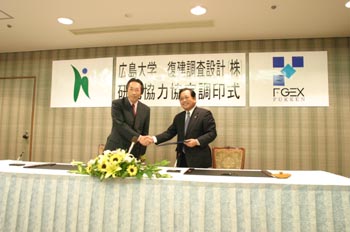 覚書に署名をすませ握手する岡田研究科長（左）と近藤社長（右）