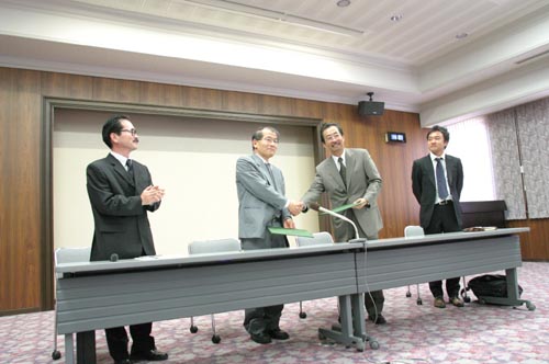 調印をすませ握手する吉里理事・副学長（左）と丹呉国際協力銀行理事